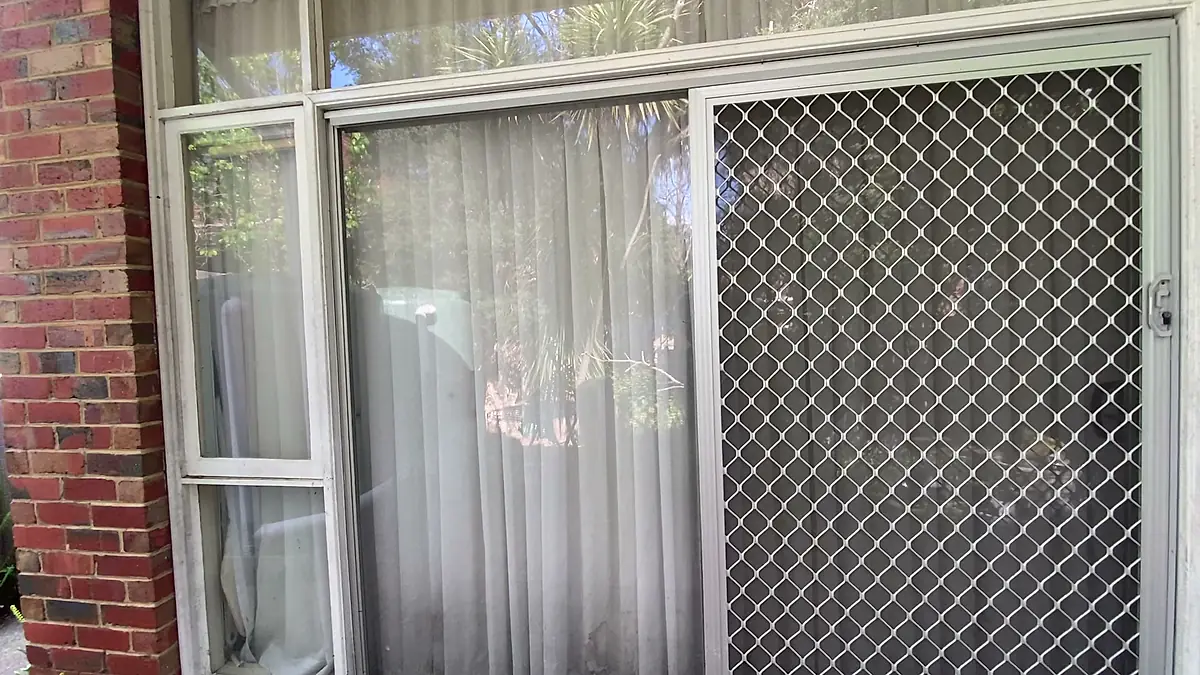 Exterior window and security screen on a brick home after cleaning