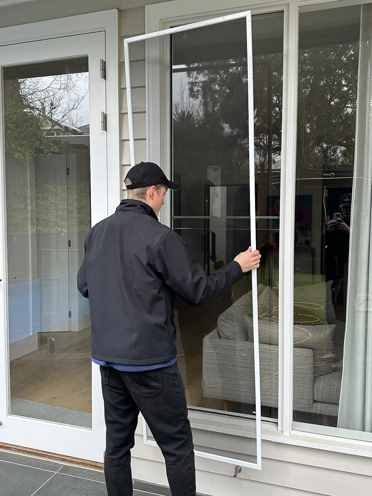 Cleaner refitting a washed fly screen to French doors