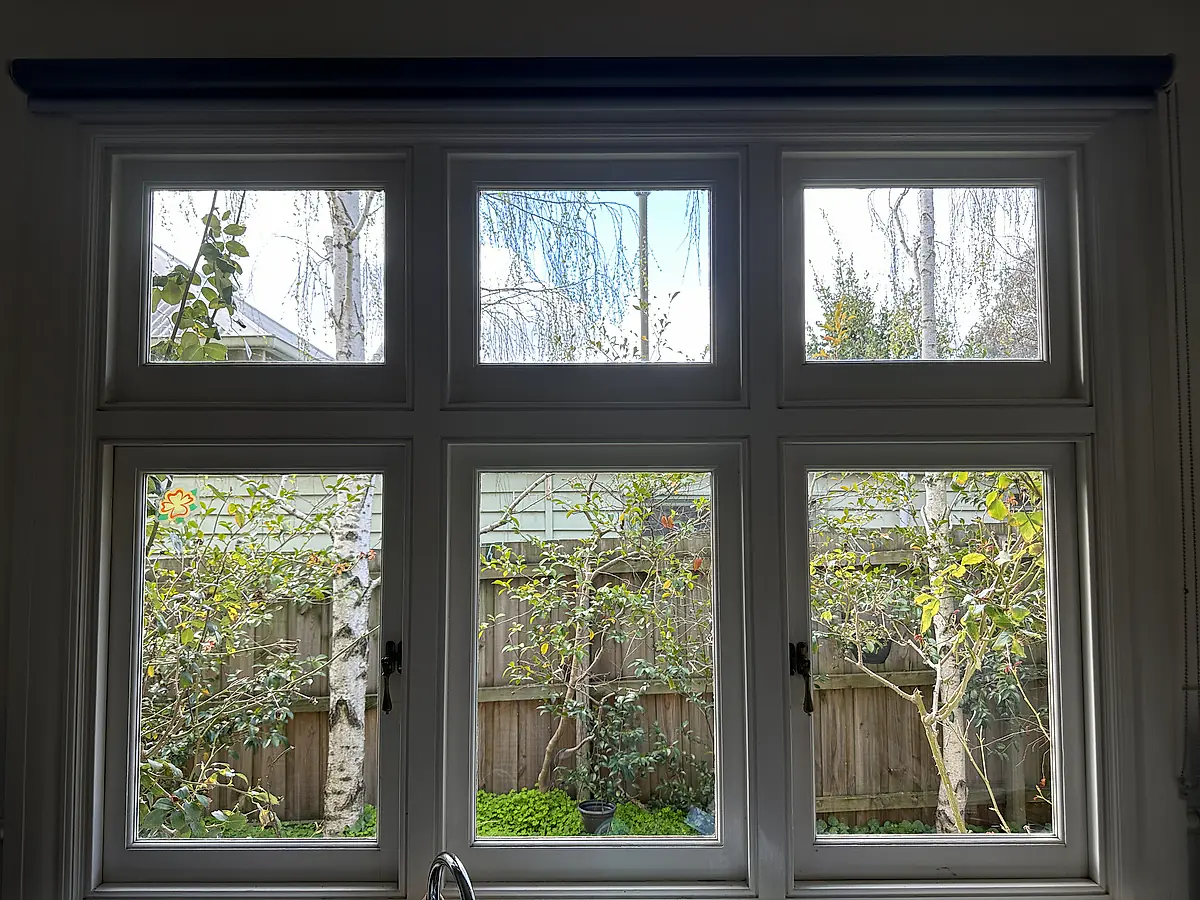 The same period timber window after cleaning, the garden sharp through clear glass