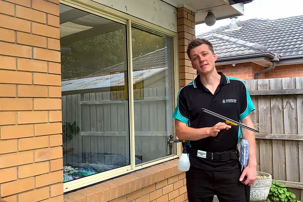 Clearwater cleaner with a squeegee outside a standard brick home, the kind of property the residential service covers