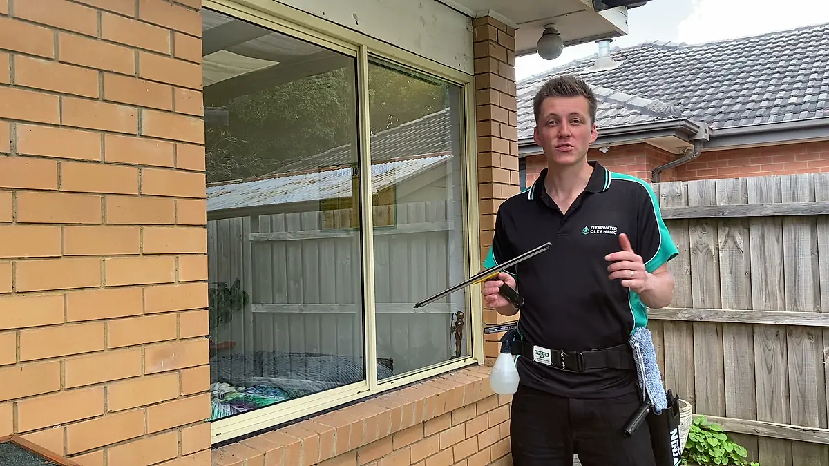 Clearwater cleaner holding a squeegee outside a suburban home